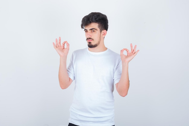 Young man showing ok gesture in t-shirt and looking happy