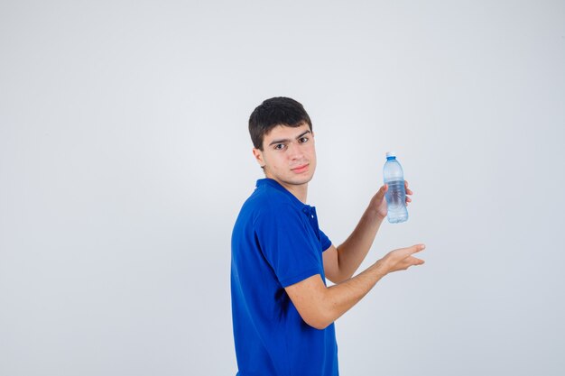 Young man showing plastic bottle in t-shirt and looking confident