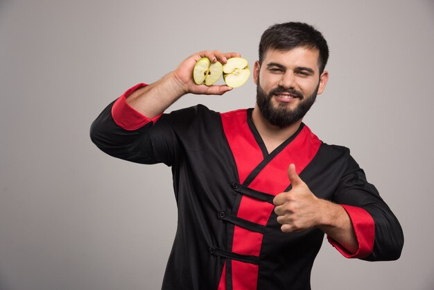 Young man showing a slices of fresh apple .