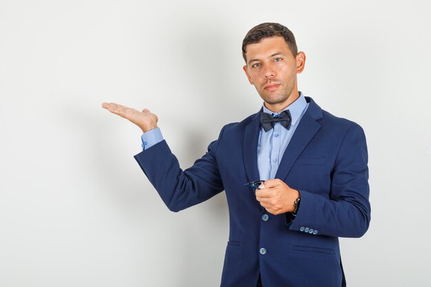 Young man showing something with glasses in suit 