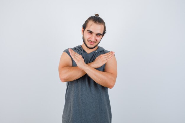 Young man showing stop gesture in hoodie and looking handsome , front view.