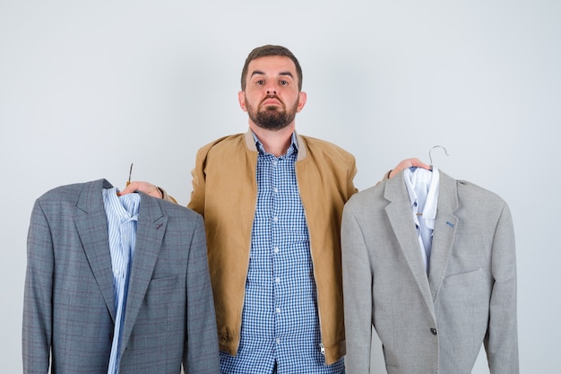 Free photo young man showing suits in jacket, shirt and looking wistful , front view.