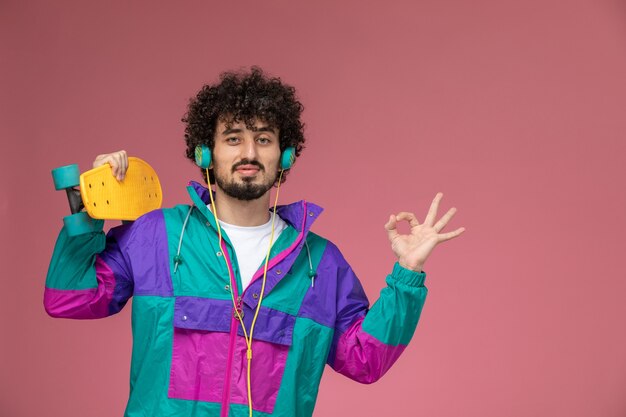 young man shows ok gesture with yellow scate board