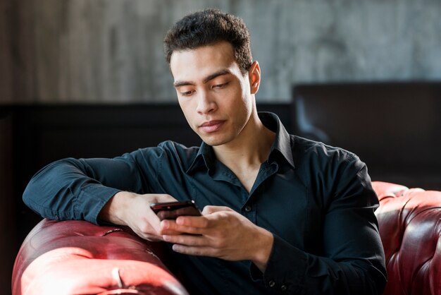 Young man sitting on armchair using mobile phone