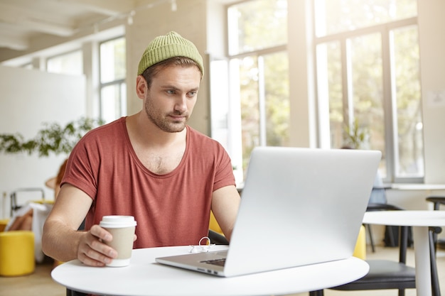 Young man sitting in cafe with laptop