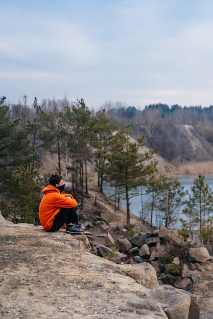 A young man sitting on the edge of a cliff 