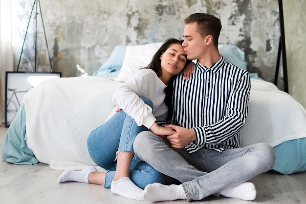 Young man sitting on floor and kissing girlfriend