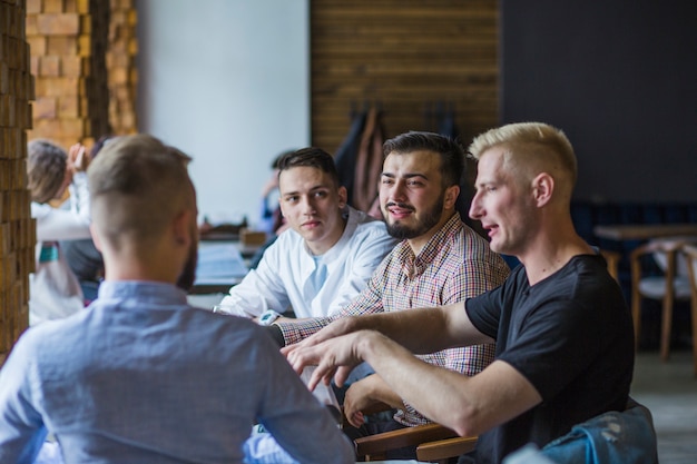 Free Photo young man sitting in restaurant explaining strategy to his friends