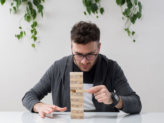 Free photo young man sitting in spectacles watches grey jacket along with plant on white