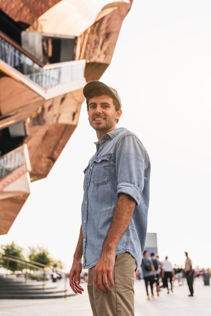 Young man smiling near a tall building