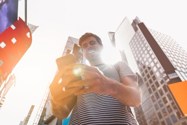 Free photo young man smiling while using his smartphone