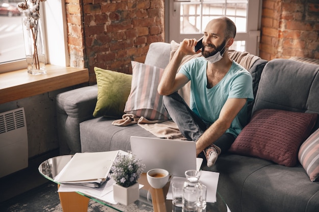 Free photo young man speaking on the phone at home while being quarantine and freelance working