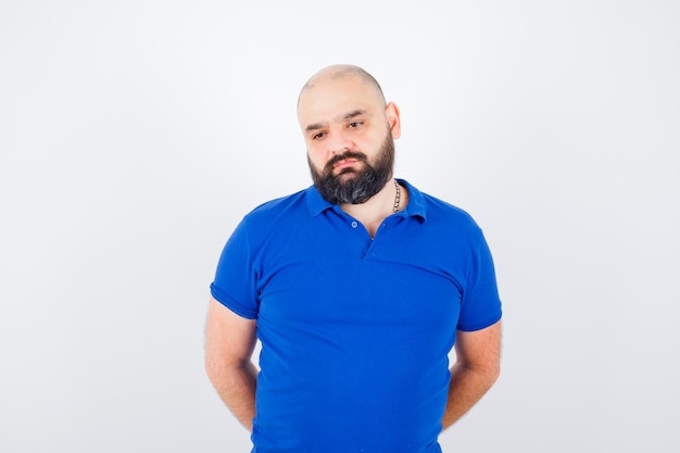 Free photo young man standing in blue shirt and looking pensive. front view.