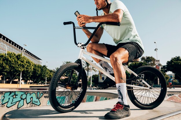 Young man standing on bmx bike looking at the phone