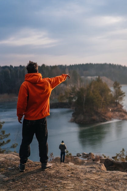 Young man standing on the edge of a cliff and pointing