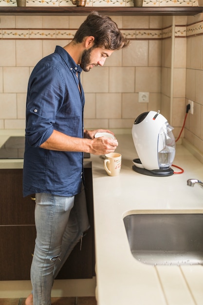 Free Photo young man standing in kitchen preparing coffee