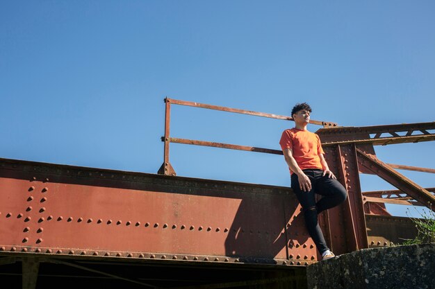 Young man standing on metallic bridge