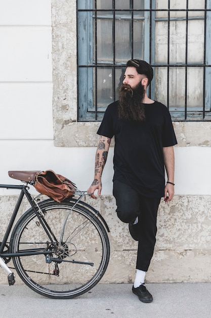 Young man standing near the bicycle looking away