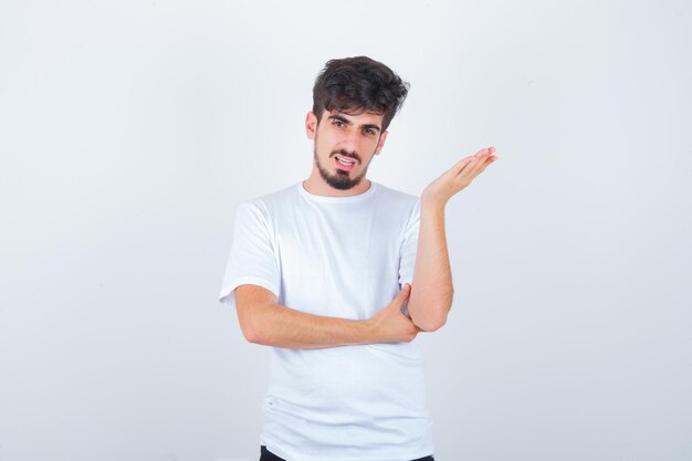 Young man standing in questioning pose in t-shirt and looking confident