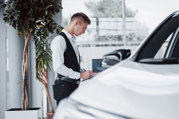 Young man standing in the showroom against cars