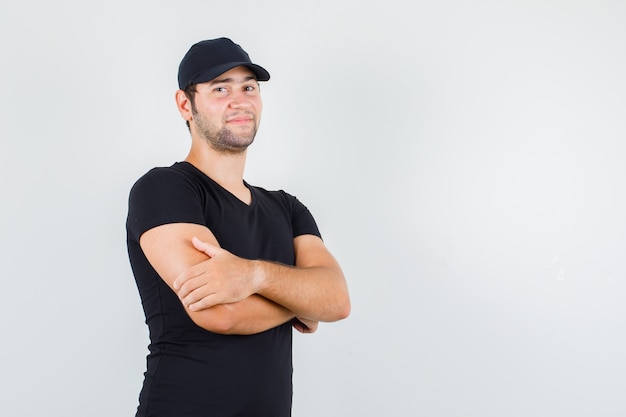 Free photo young man standing with crossed arms in black t-shirt