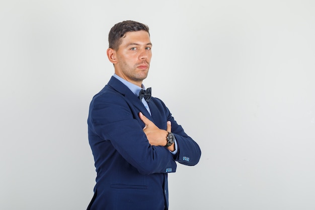 Young man standing with crossed arms in suit and looking serious.