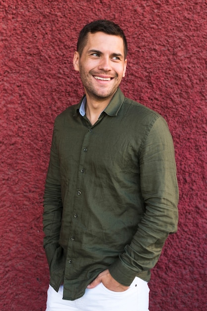 Young man standing with hand in pocket near red wall