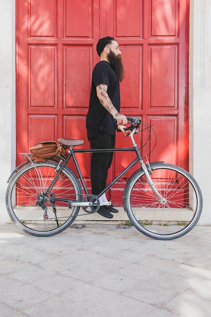 Free photo young man standing with his bicycle looking for someone