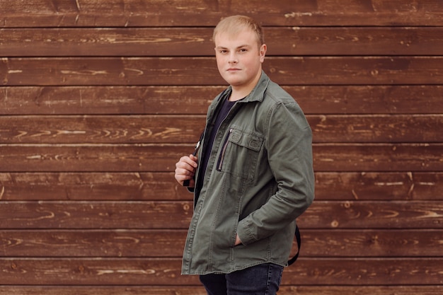 Free photo young man standing next to a wooden wall