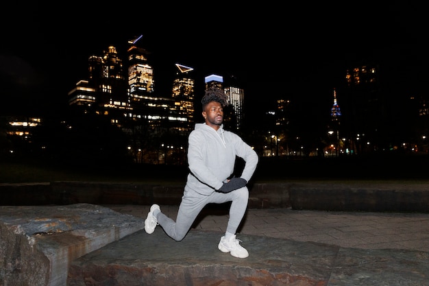 Free photo young man stretching at night in the city