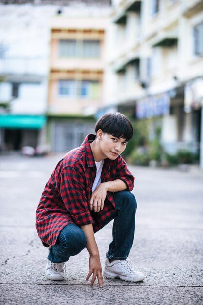 A young man in a striped shirt sitting on the street