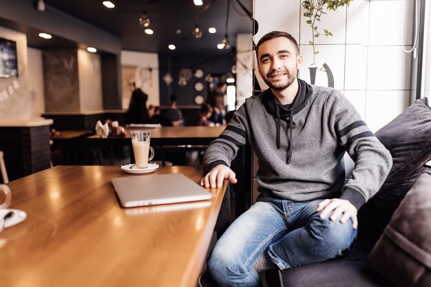 Young man student with laptop computer drink coffee in cafe