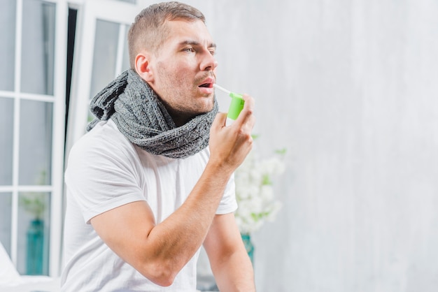 Free photo young man suffering from cold treats her throat with a spray