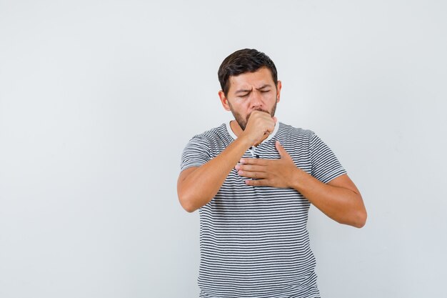 Young man suffering from cough in t-shirt and looking sick. front view.