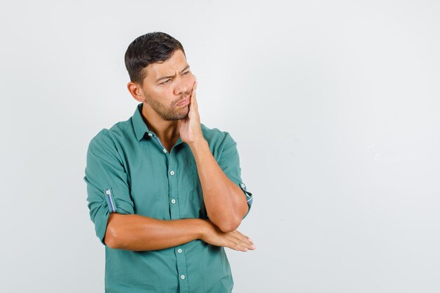 Young man suffering from toothache in shirt and looking sad