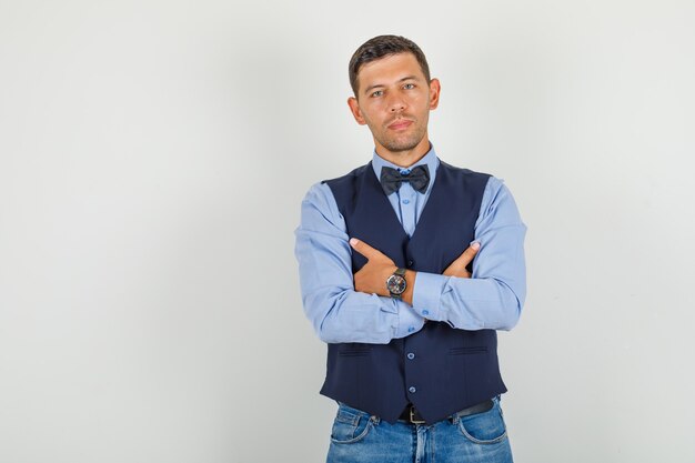 Young man in suit, jeans standing with crossed arms 