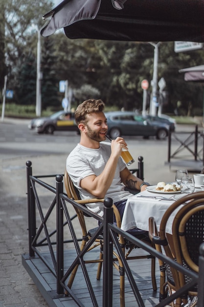 Free photo young man in a summer cafe on the terrace has breakfast