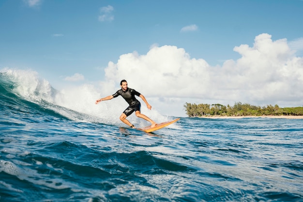 Young man surfs ocean clear water waves