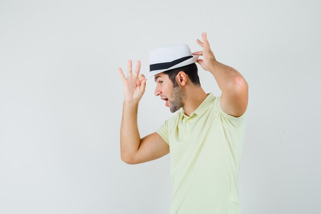 Young man in t-shirt adjusting his hat and looking elegant