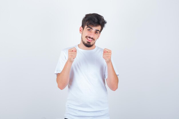 Young man in t-shirt showing fig sign and looking funny