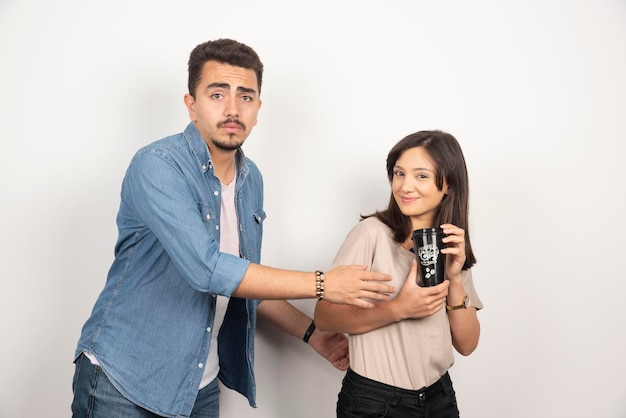 Young man taking away a cup of coffee from girl.