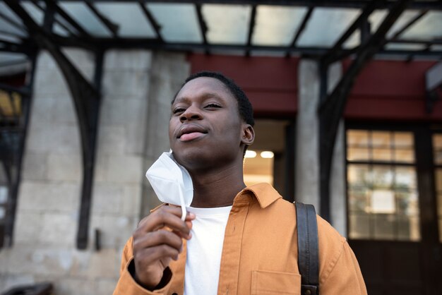 Young man taking mask off medium shot