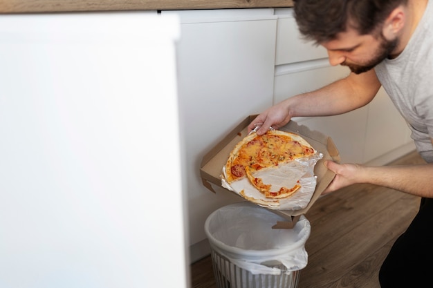 Free photo young man throwing away food in the trash