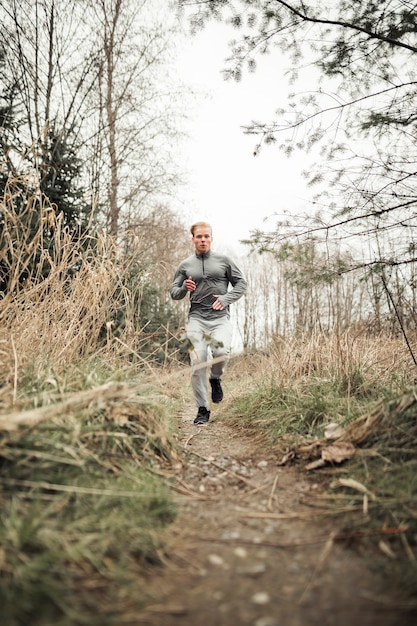 Free photo young man trail running in the forest