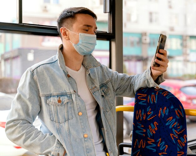 Young man travelling by city bus using smartphone