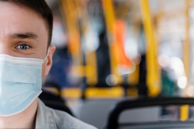 Young man travelling by city bus wearing surgical mask