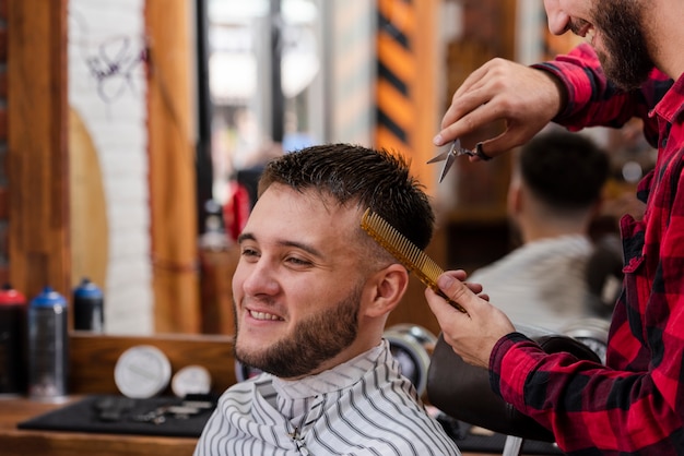 Free photo young man trimming with scissors and comb