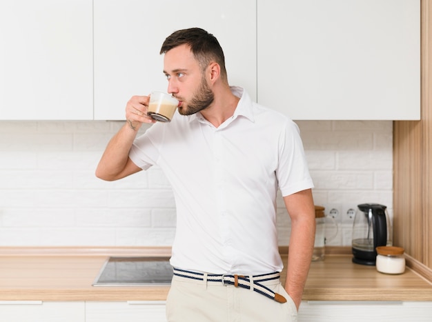 Young man in tshirt sipping a coffee in the kitchen