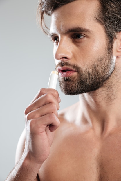 Free photo young man using colorless lipstick