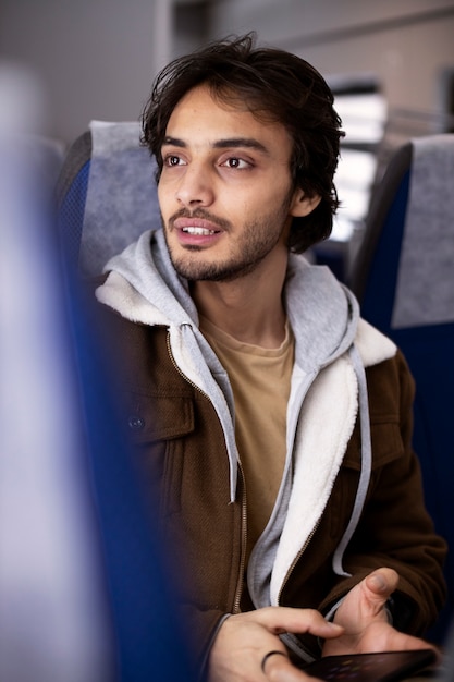 Free Photo young man using his smartphone while traveling by train